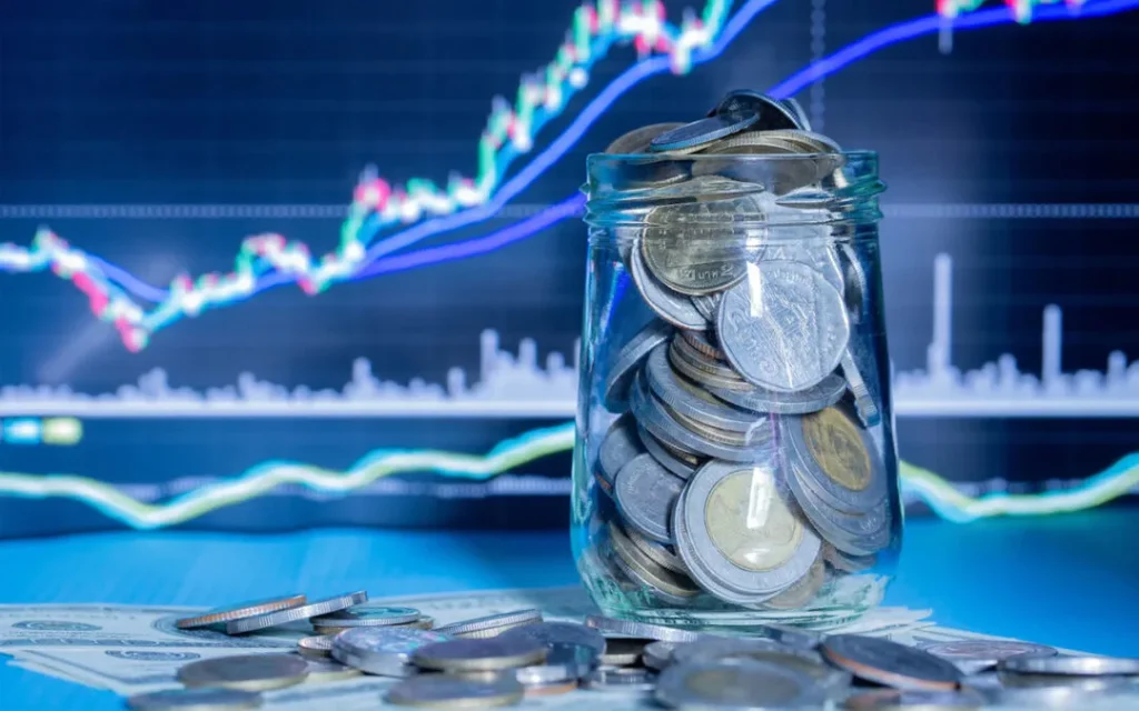 Imagem de um pote de moedas com um grafico financeiro atras